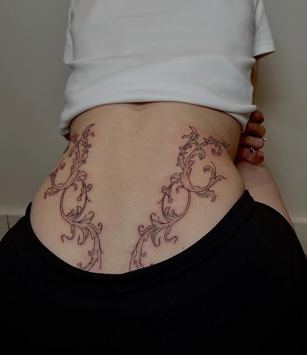 Tatouage ornement baroque symétrique bas du dos — lamiam_tattoo