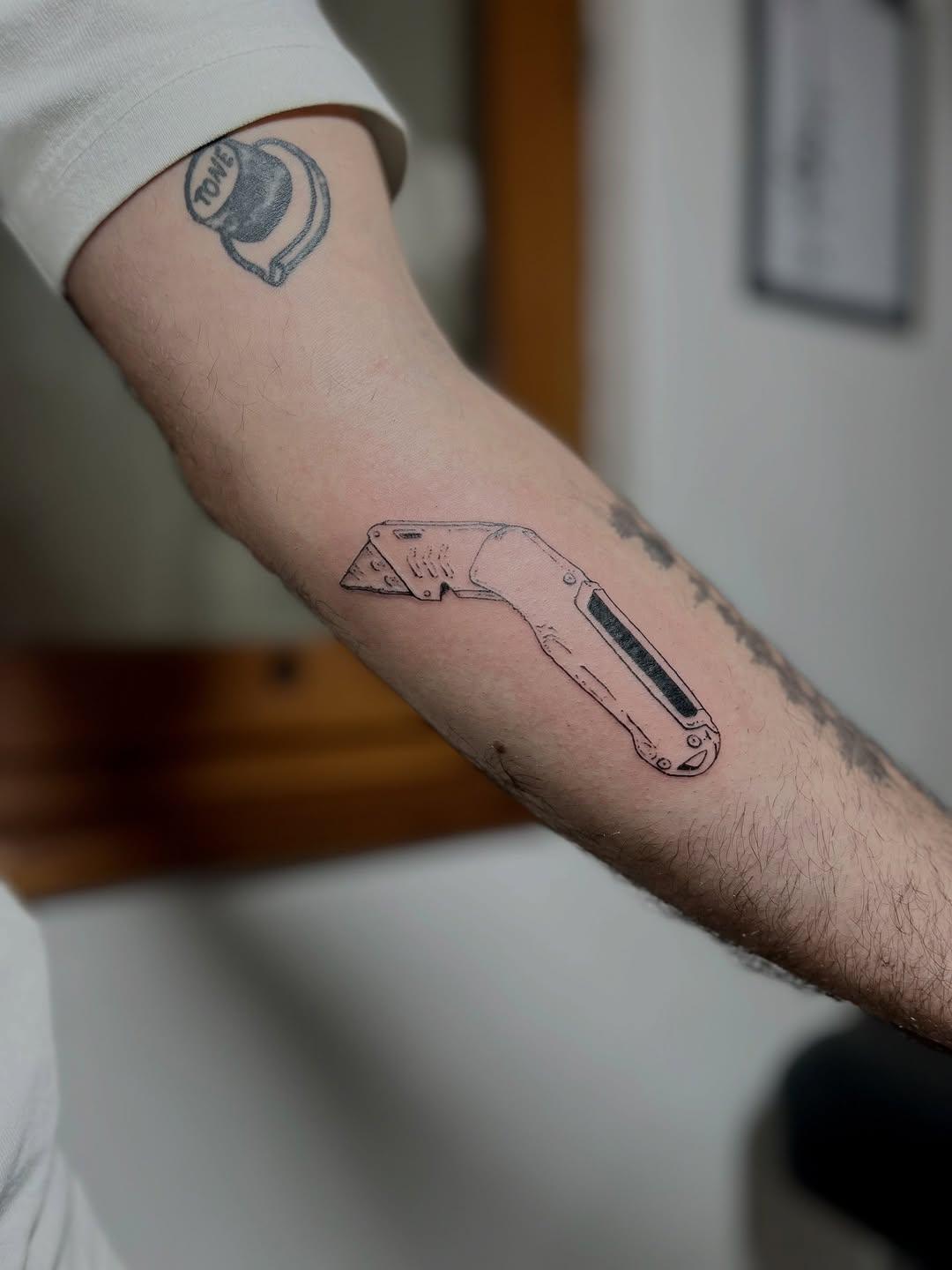 Tatouage d'un cutter en fine line sur l'avant-bras — konkrete.ttt