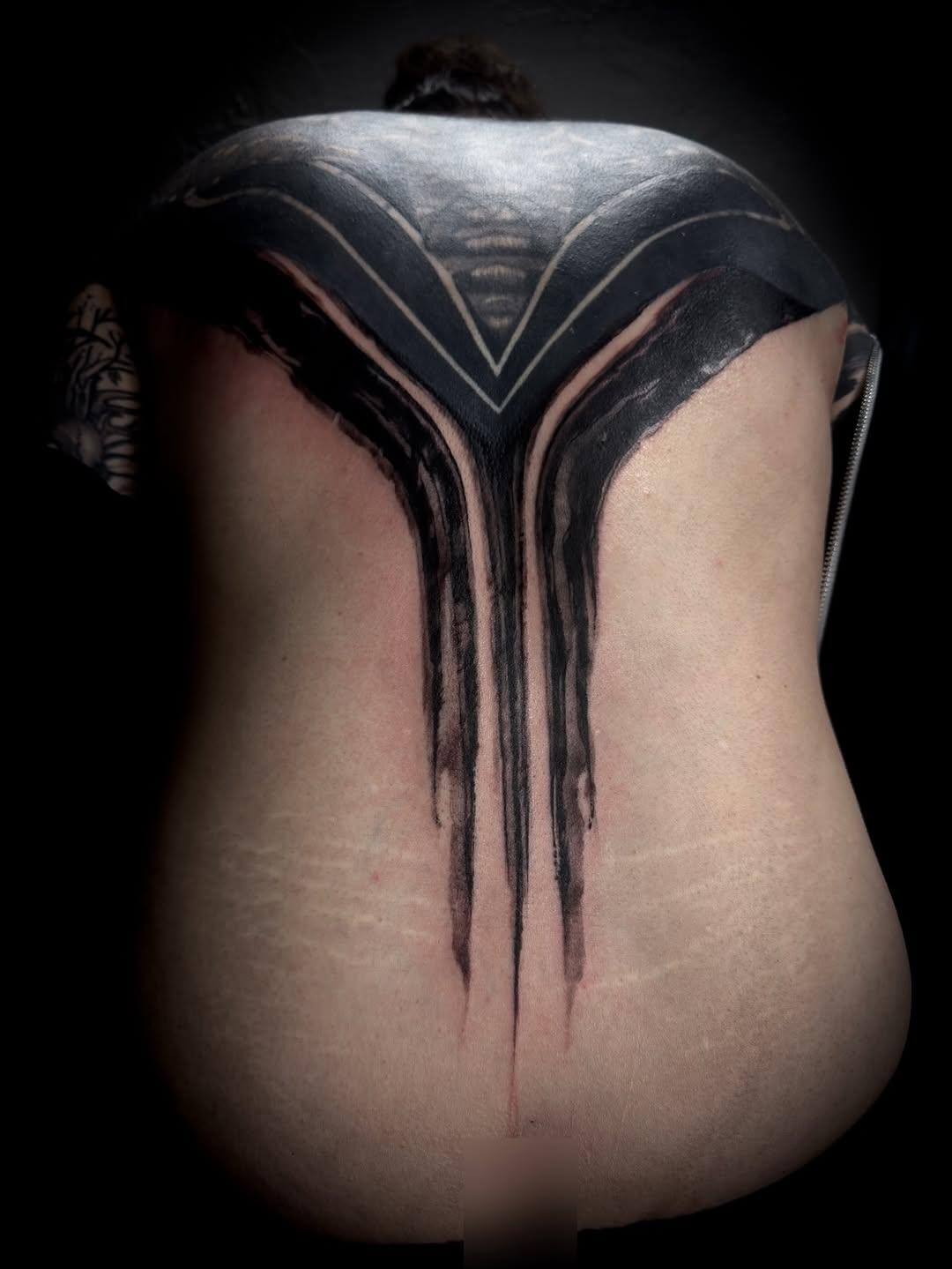 Brushwork backpiece tattoo with dark dripping ink and geometric face