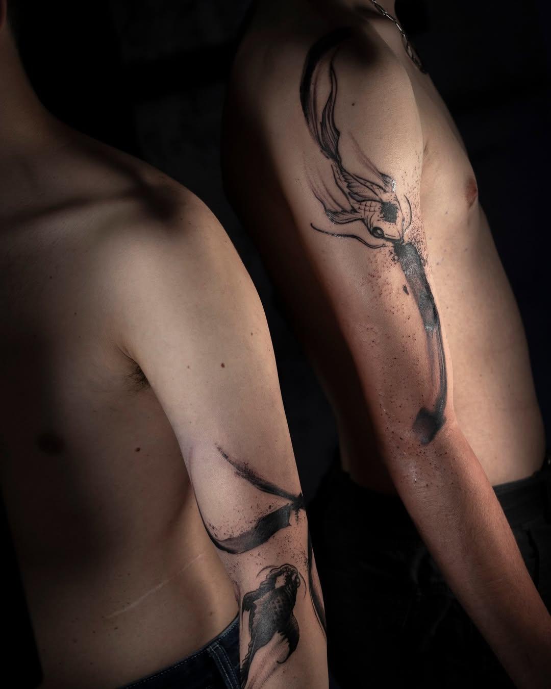 Dark brushwork fish tattoos on shoulder and torso of two people