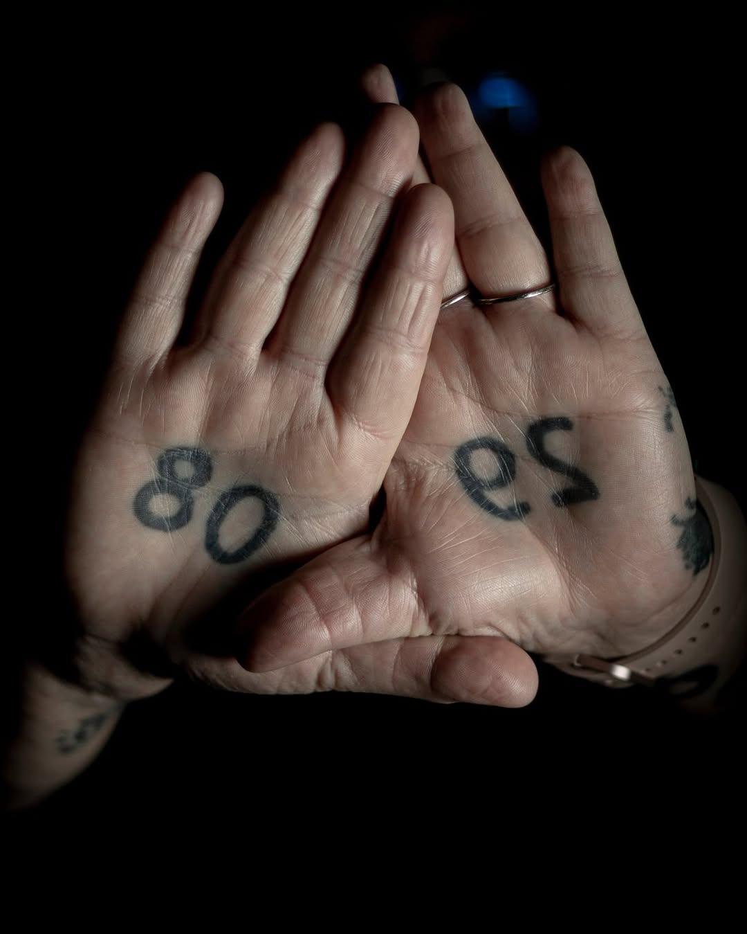 Healed number tattoos on both palms — 80 and 29