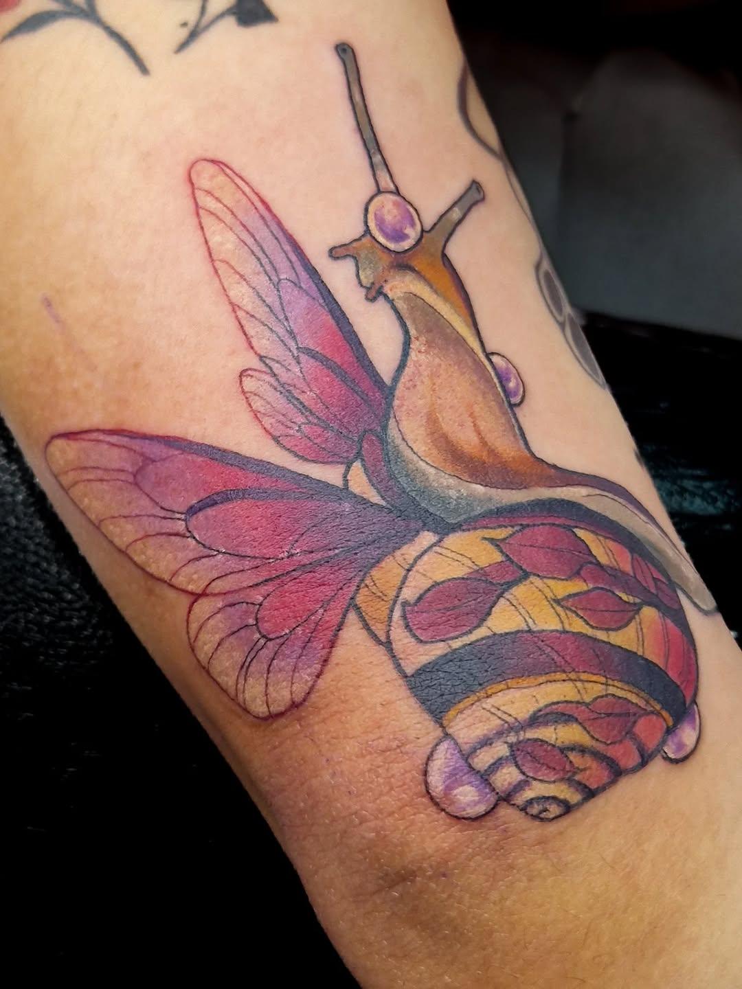Tatouage escargot ailé coloré sur avant-bras — madameclouds_tattoo